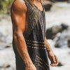 Man wearing a sleeveless black and gold patterned shirt standing by a stream.