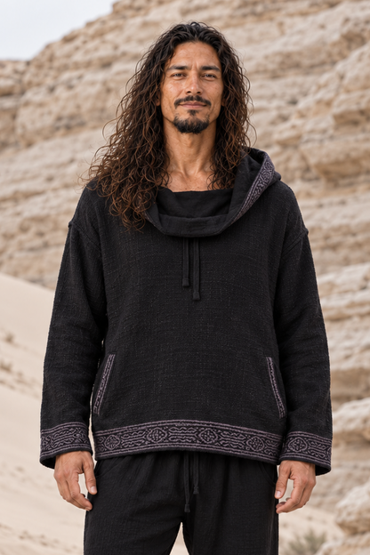 Front view of man in black block-printed cotton hoodie, hood down as a loose cowl neck, drawstring and pockets visible