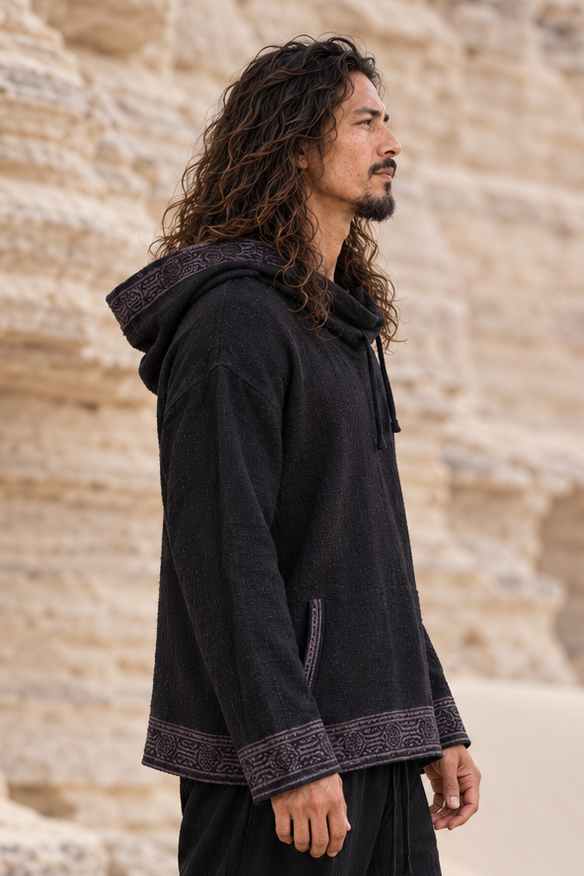 Side view of man in black cotton hoodie, hood down, looking out across a desert canyon